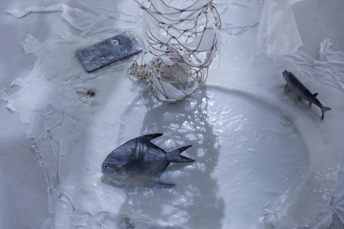 〈流變空間〉，2022，樹酯、漁網、照片、木馬、繪製後的模型魚、手機、海邊菸蒂、痱子粉、Antari ICE-101，依場域而定，作品局部的封面圖