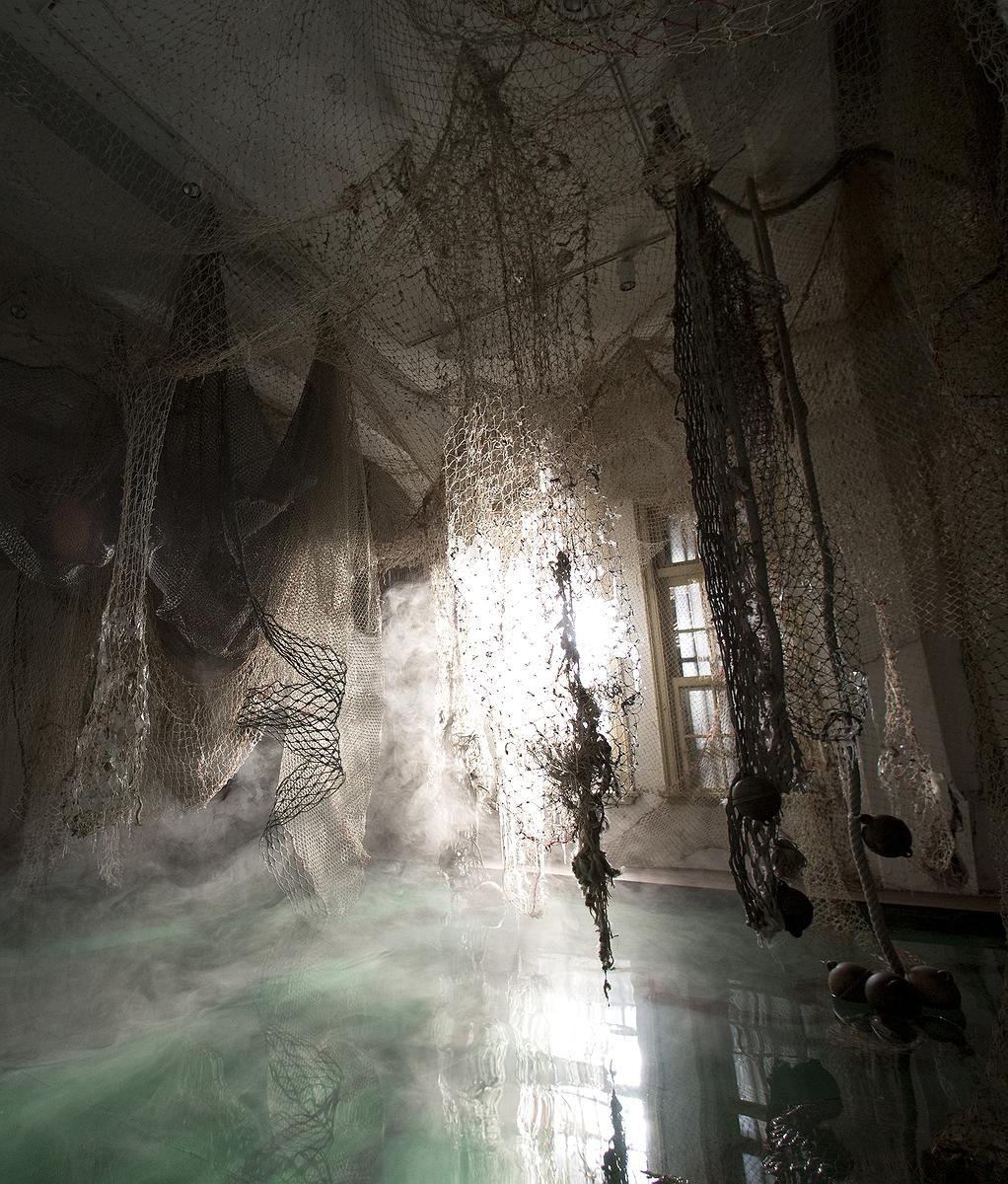 〈迷網之境〉，2018，漁網、繩子、樹酯、Antari ICE-101冰塊煙霧機、ARRI燈，水池、影像，-1沉水抽水馬達、浮球，正濱舊漁會大樓，基隆，局部圖。的封面圖